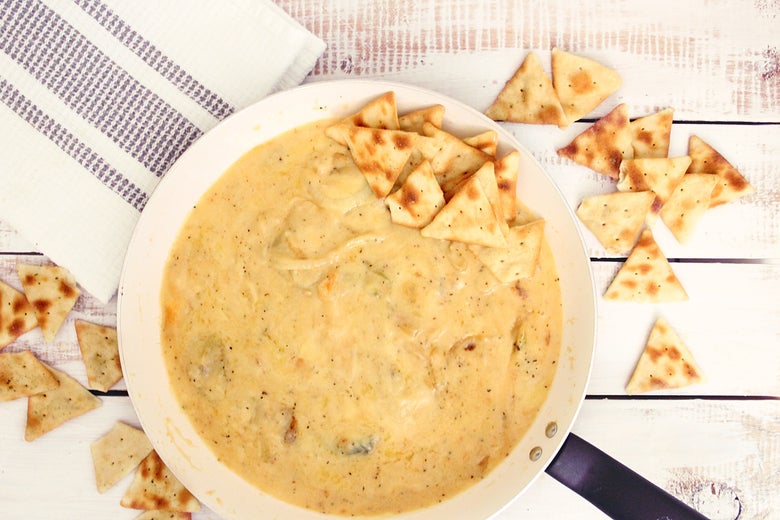 A bowl of creamy dip with some crackers around it.